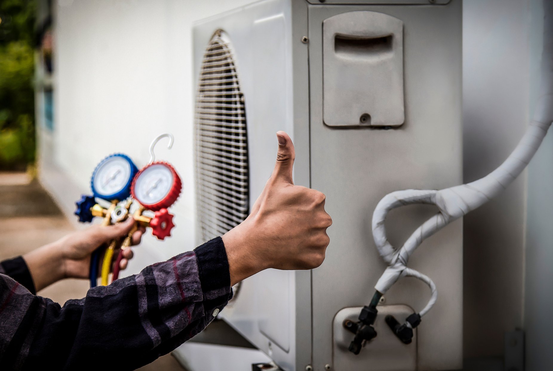 Air conditioning, HVAC service technician using gauges to check refrigerant and add refrigerant.